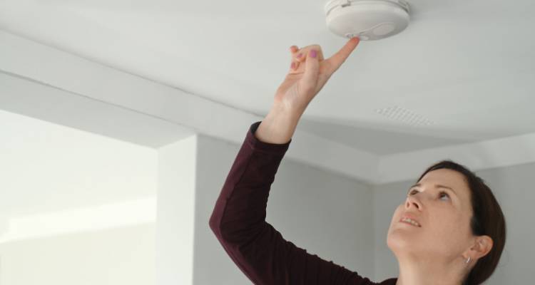 person testing smoke alarm