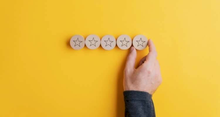 person placing five wooden stars on yellow background