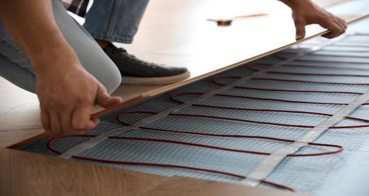tradesperson laying flooring on top of underfloor heating