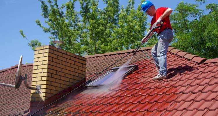Person power washing a roof