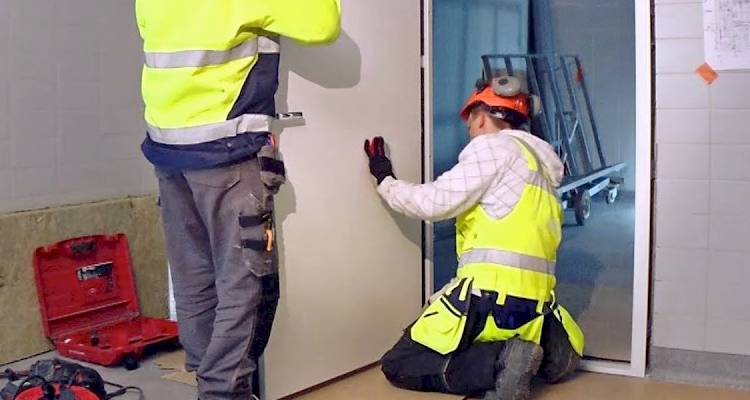 Two tradespeople installing a fire door