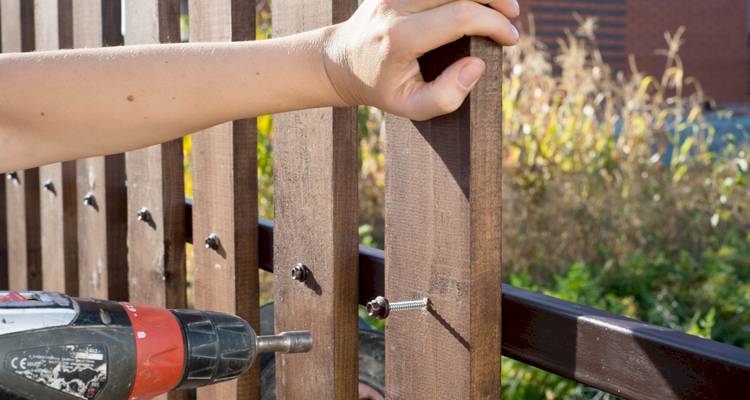 Person drilling a wood fence