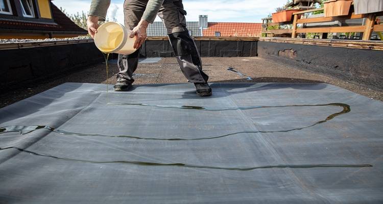man pouring liquid on roof