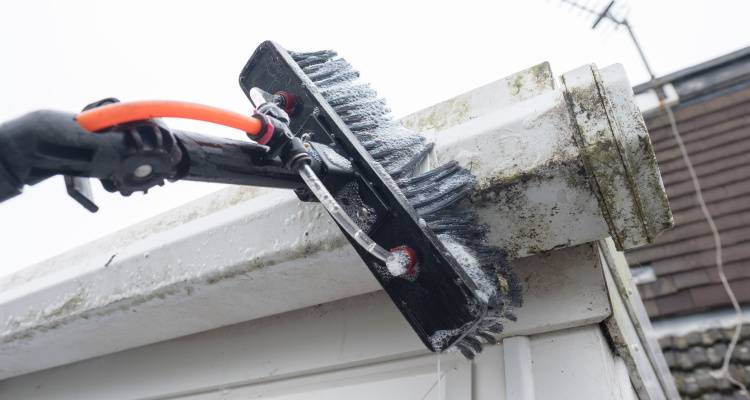 cleaning a gutter with a brush