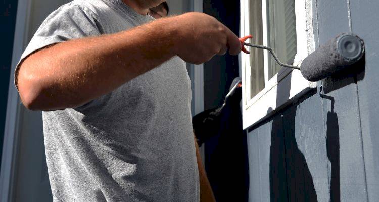 house extension cost guide — tradesperson painting the exterior of a house extension