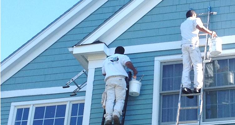 Two men painting a house blue