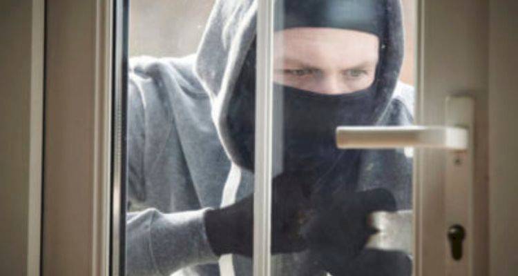 locksmith cost guide — person simulating a break-in by attempting to open a door with tools