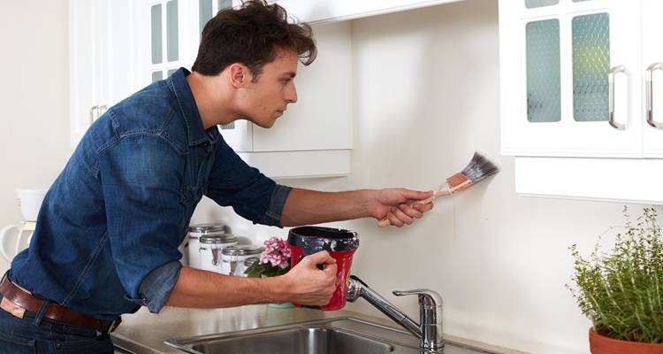 man painting behind sink