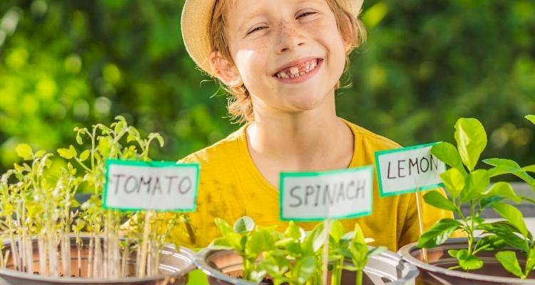 Young child smiling in front of garden plants
