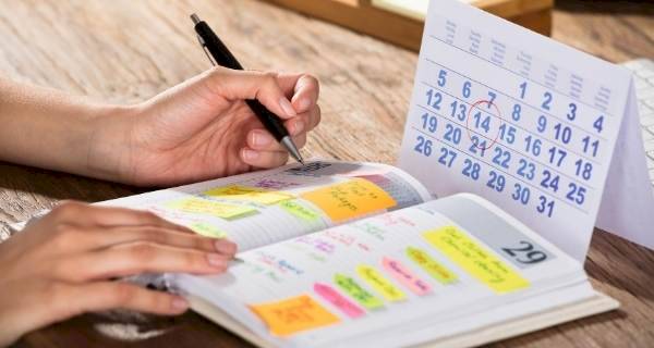 person writing in a diary with a calendar