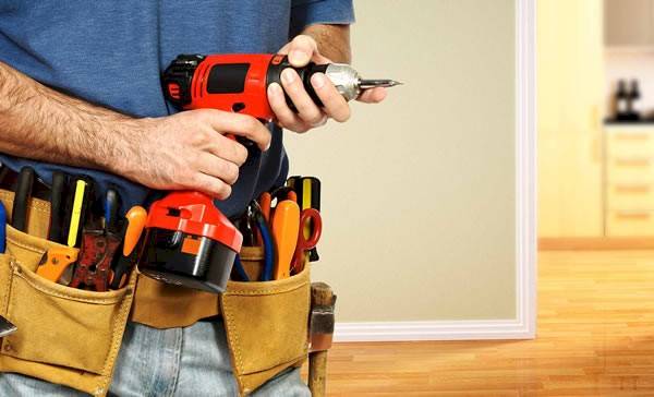 Man holding a drill with utility belt on