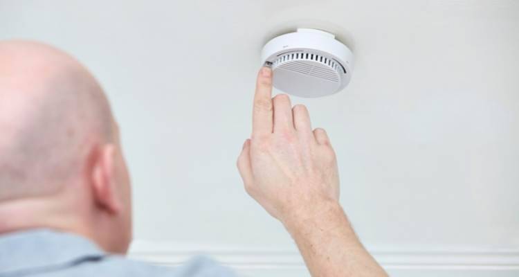 hand checking smoke alarm