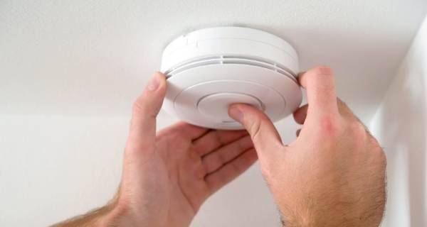 hand checking smoke alarm