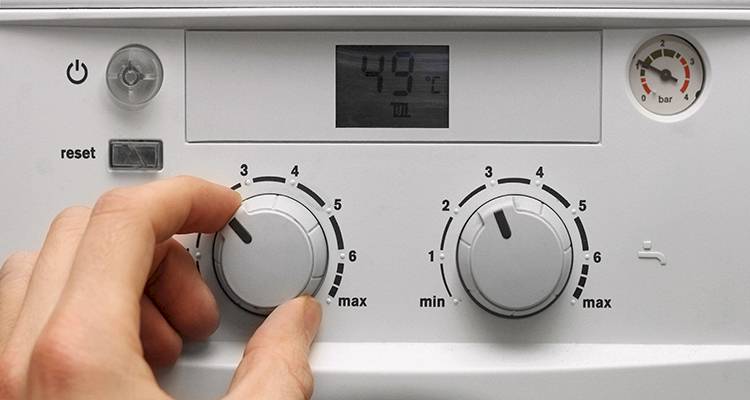 combi boiler installation cost guide — closeup of a hand adjusting the temperature on a boiler control panel