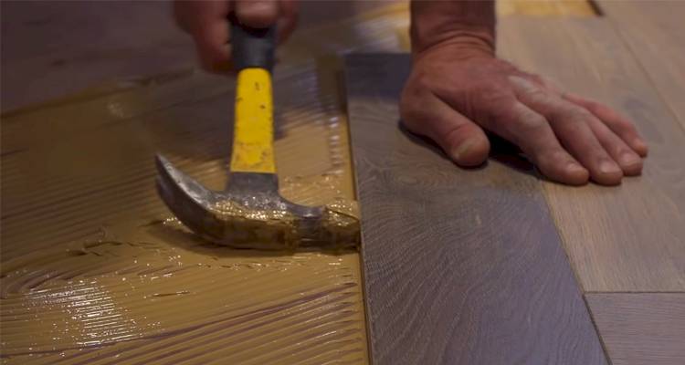 man hammering wood floor