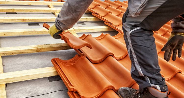 roofing specialist laying clay tiles for a roof replacement job