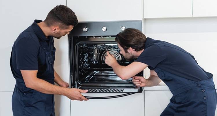 two men fixing oven