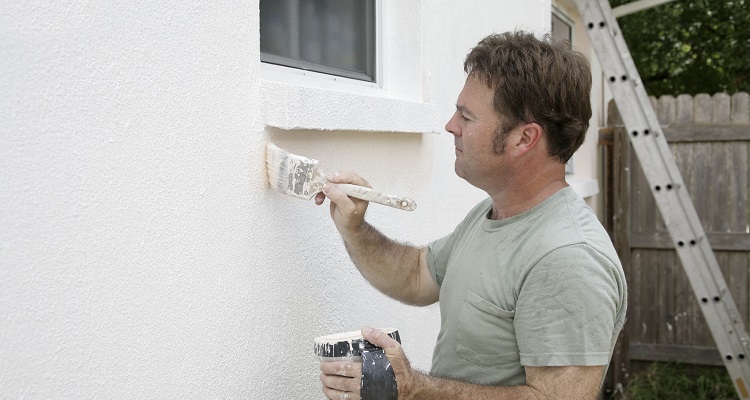 a man painting outside of house