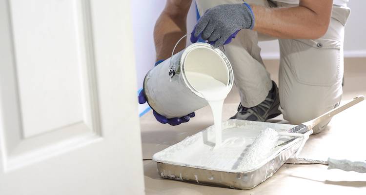 closeup of a person pouring out paint into a tray