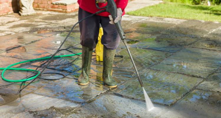 person jet washing patio