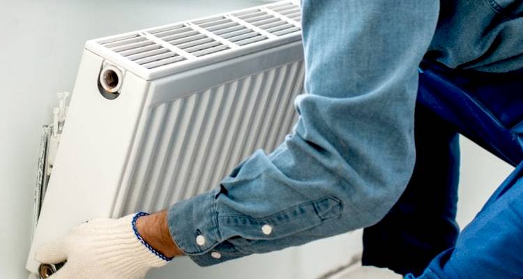 Person installing a radiator on the wall