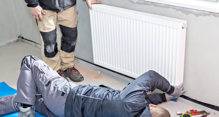 Two men installing a radiator