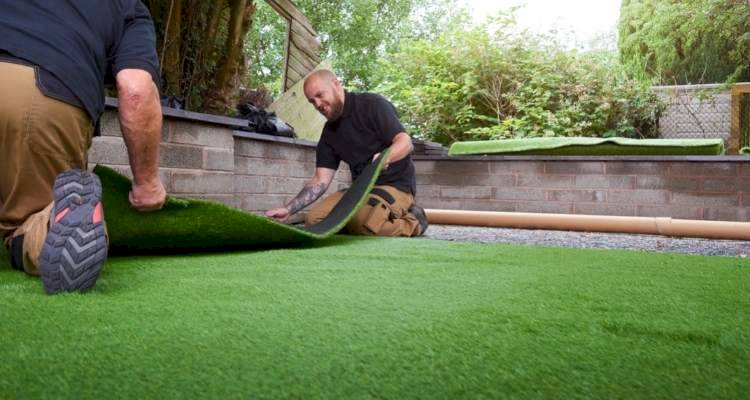 two people laying fake grass lawn