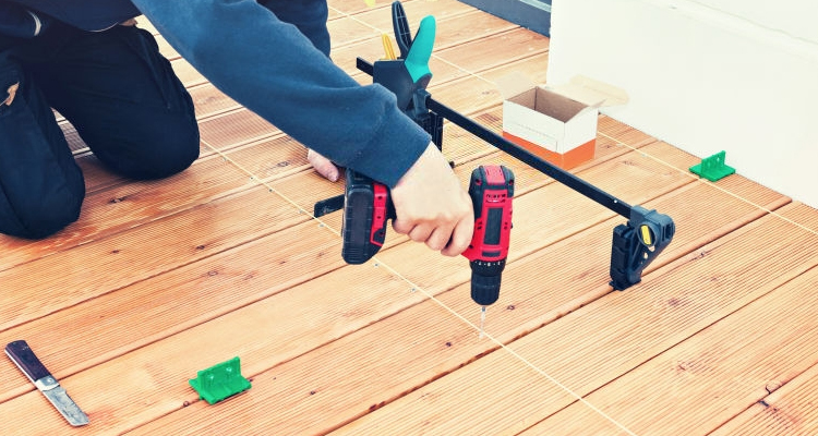 person installing timber decking with various tools