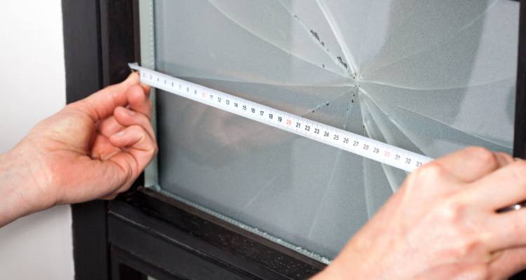 person measuring a broken window