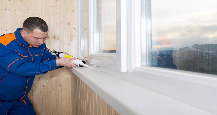 tradesperson applying sealant after installing a new window sill