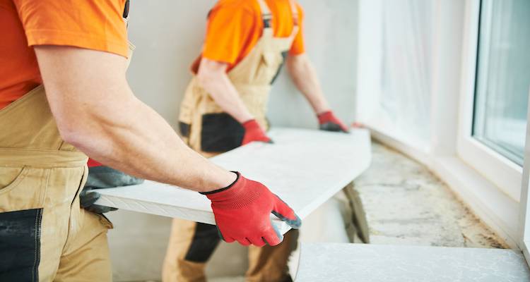 two people working together to fit a heavy window sill replacement
