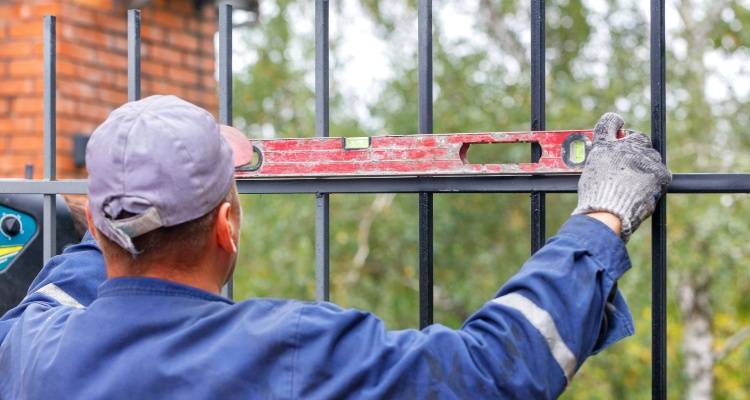 man installing wrought iron fence and gate