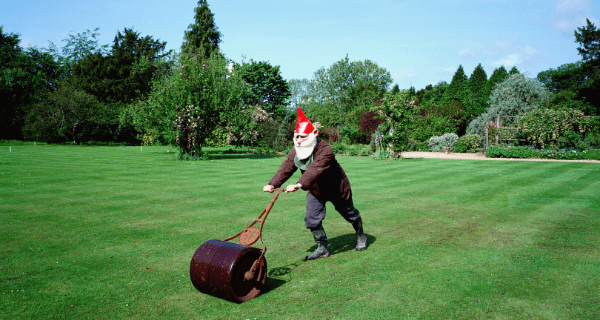 Man in a gnome outfit mowing the lawn