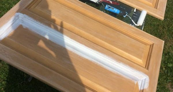 Painting kitchen cupboard doors in the garden with white paint