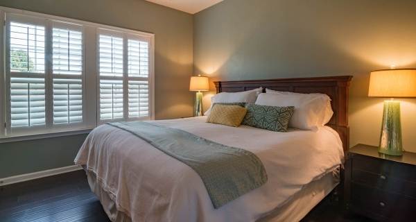 green bedroom with warm lamp lighting either side light