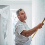 man painting a wall white