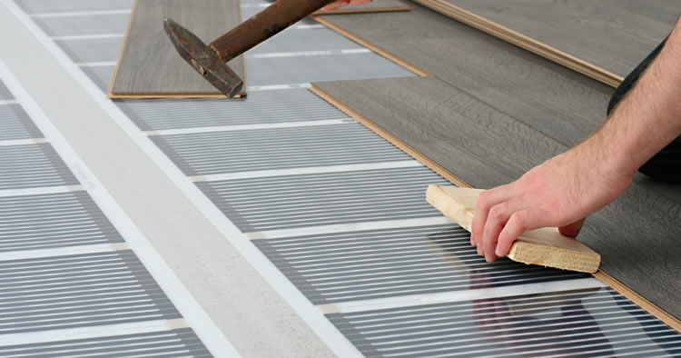 person installing laminate flooring over underfloor heating
